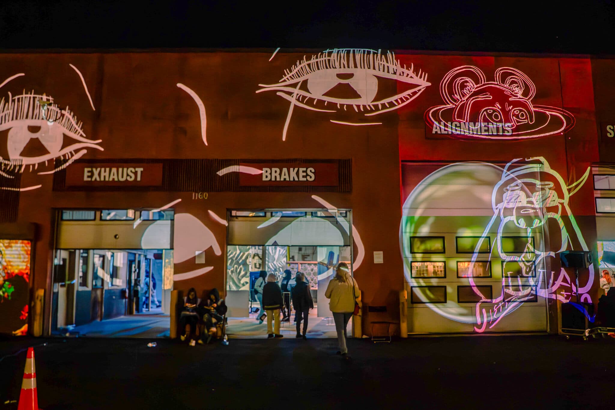 Tech light projections cover the facade of a former tire shop.