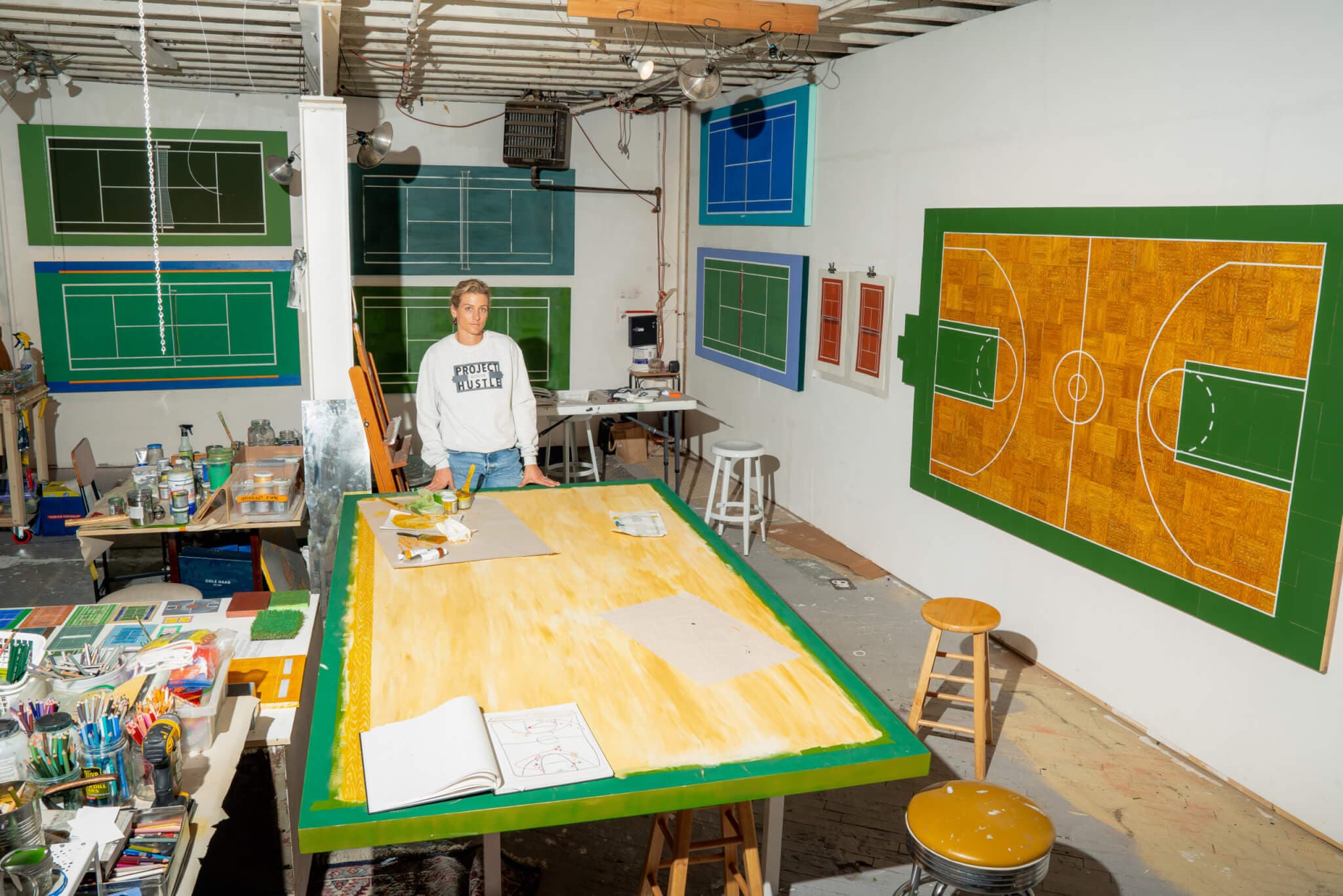 A woman stands beside a wooden board intended to be an art piece.