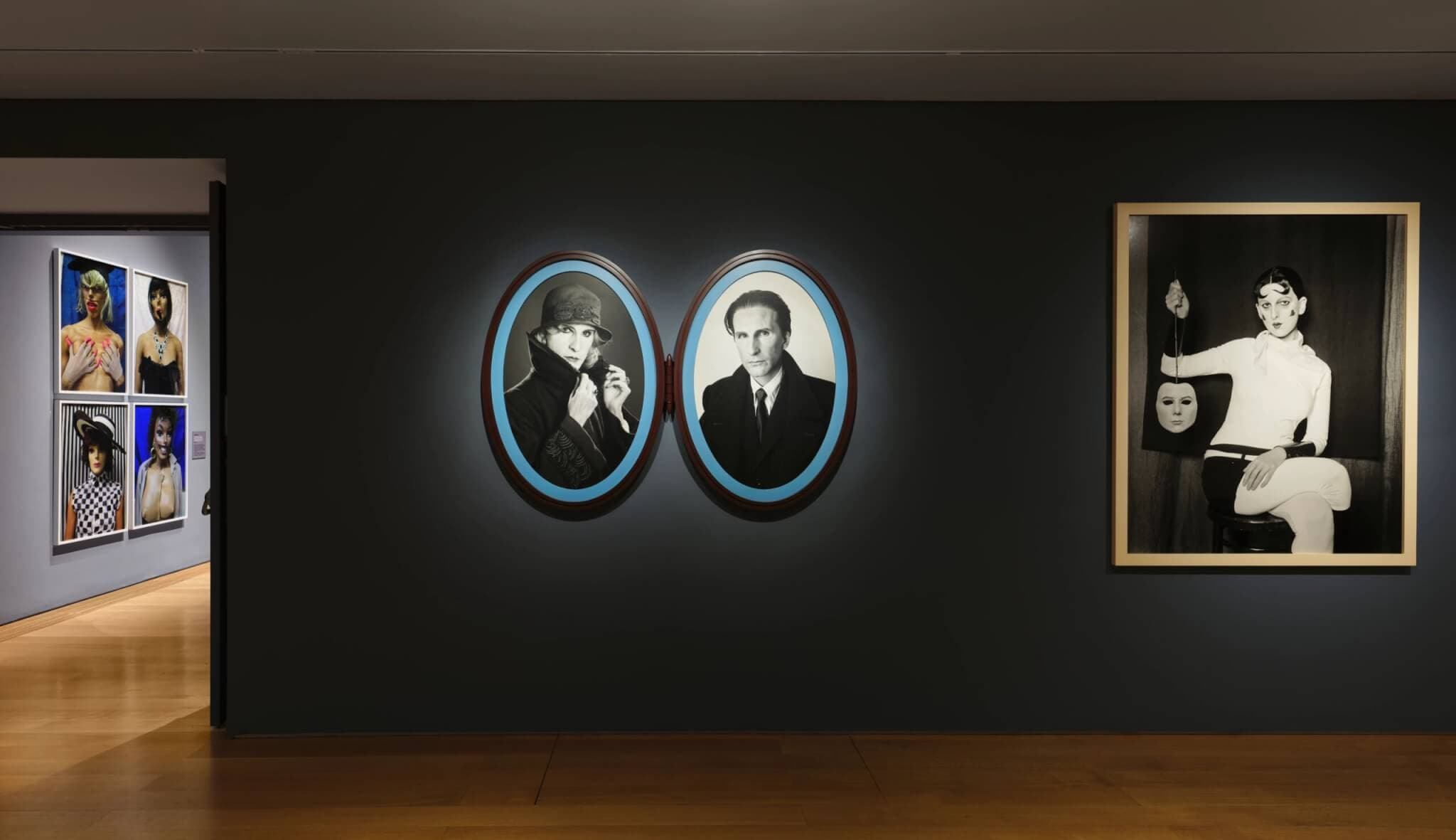 Photographs lit from behind occupy a dark gallery wall.