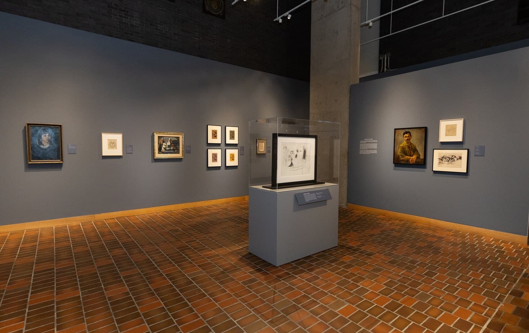 Paintings and drawings mounted on the walls of a gallery.