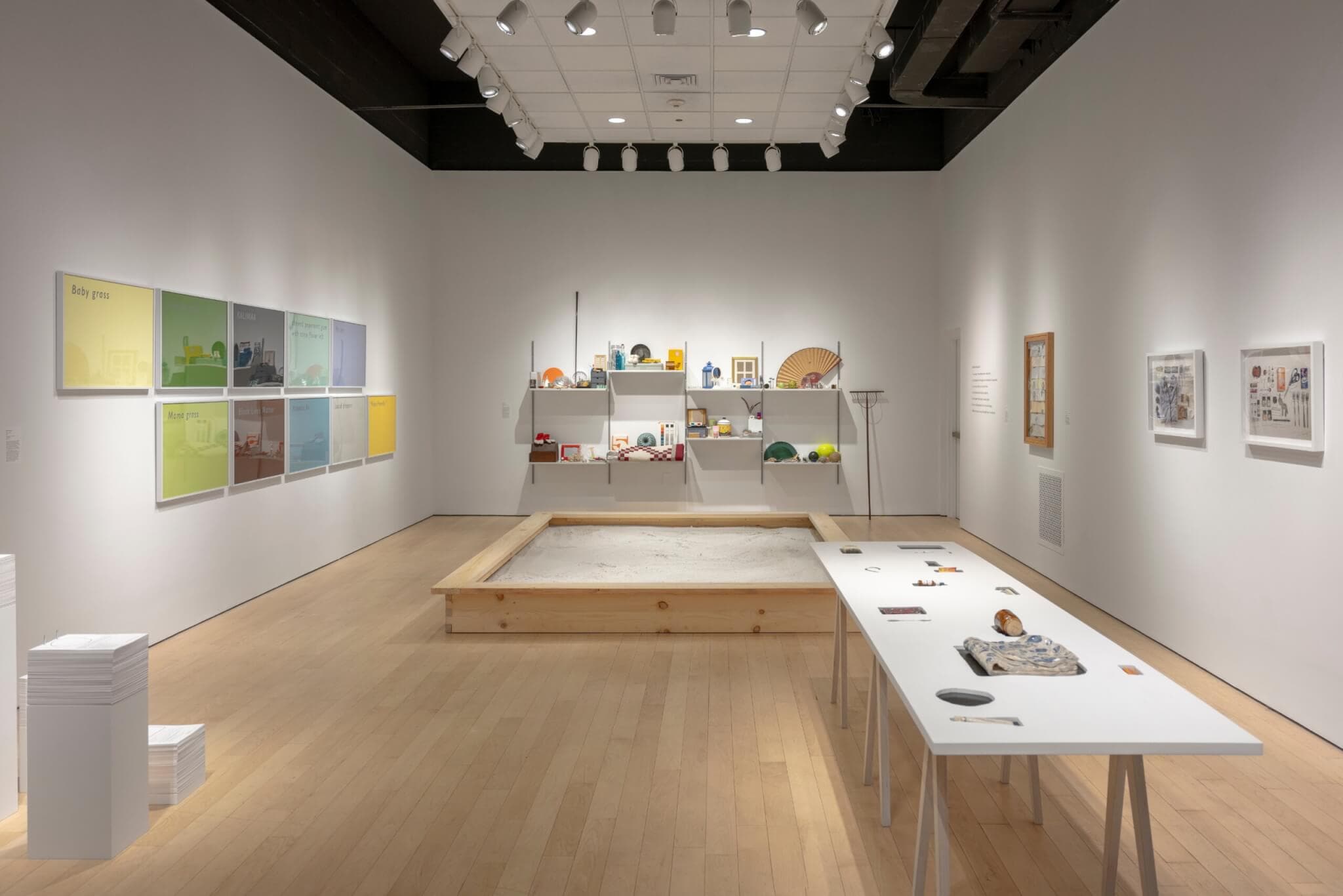Color swatches, a sandbox, and an assortment of objects in a gallery space.